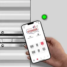 A hand holding smartphone with Storage Rentals of America app to unlock storage unit with green access light.