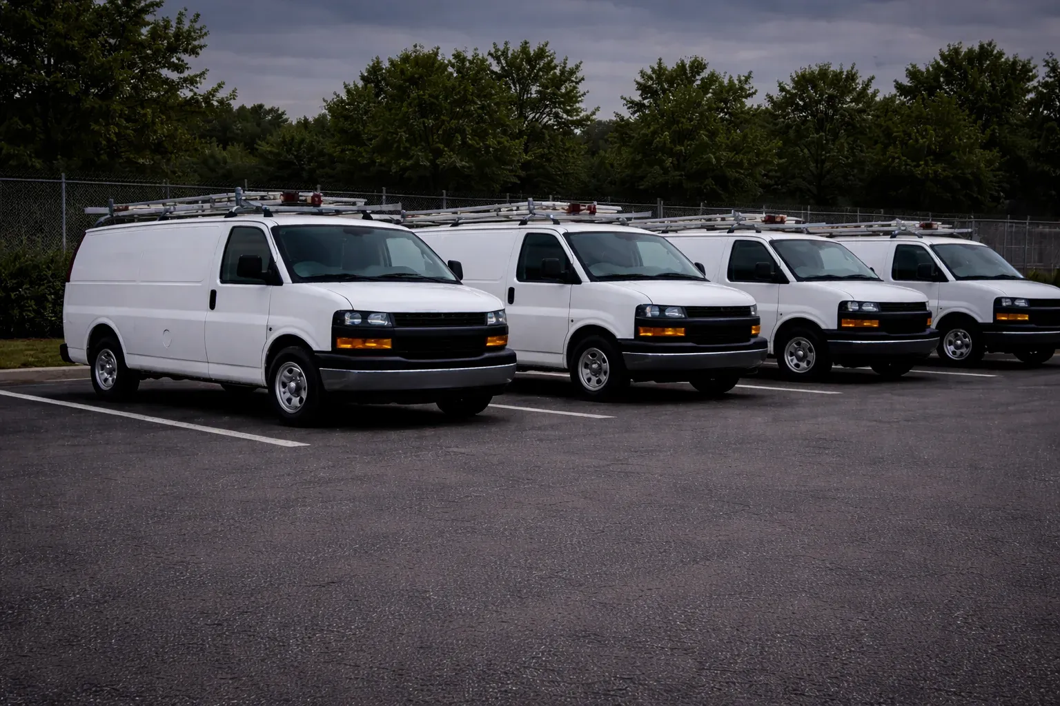 Vans parked in a row under an overcast sky.