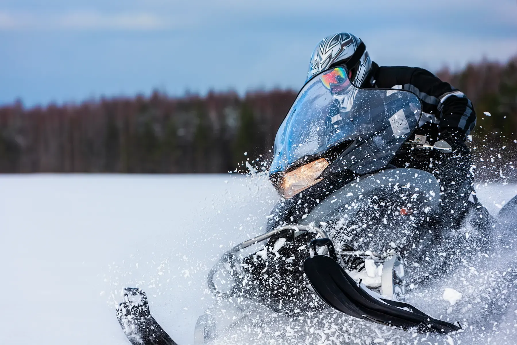 A man driving a snowmobile in an open area.