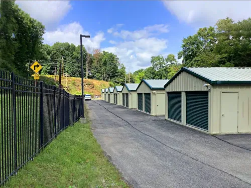 Drive up storage units with at a Storage Rentals of America facility, fenced perimeter and asphalt access road under blue sky.